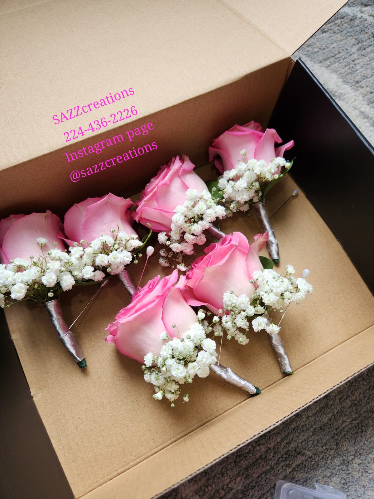 Pink rose boutonnieres with baby's breath wrapped in silver ribbon in a gift box