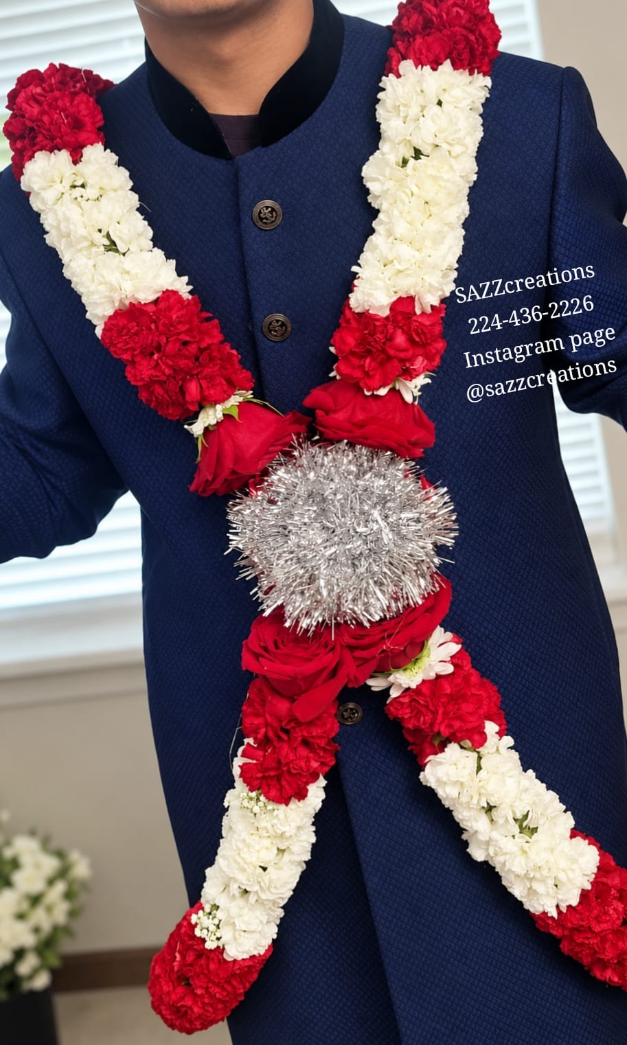Red and white carnation baddi haar with red roses and silver tinsel centerpiece on a navy sherwani