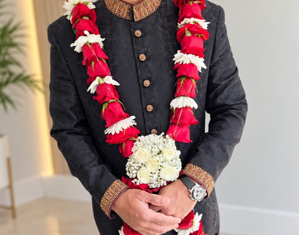 Red rose baddi haar with white rose and baby's breath cluster on a black sherwani