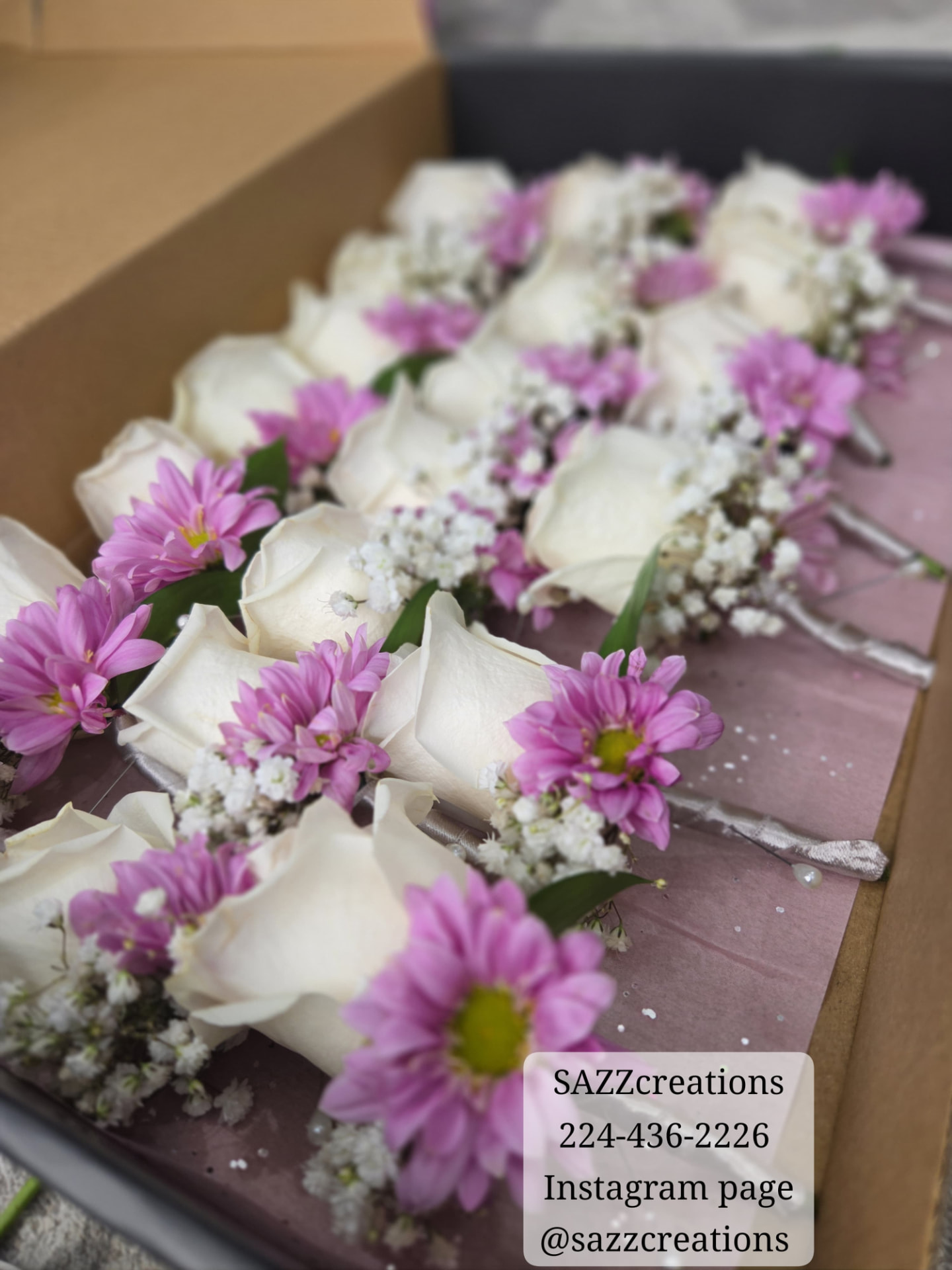 White rose and pink daisy boutonnieres in a gift box with baby's breath