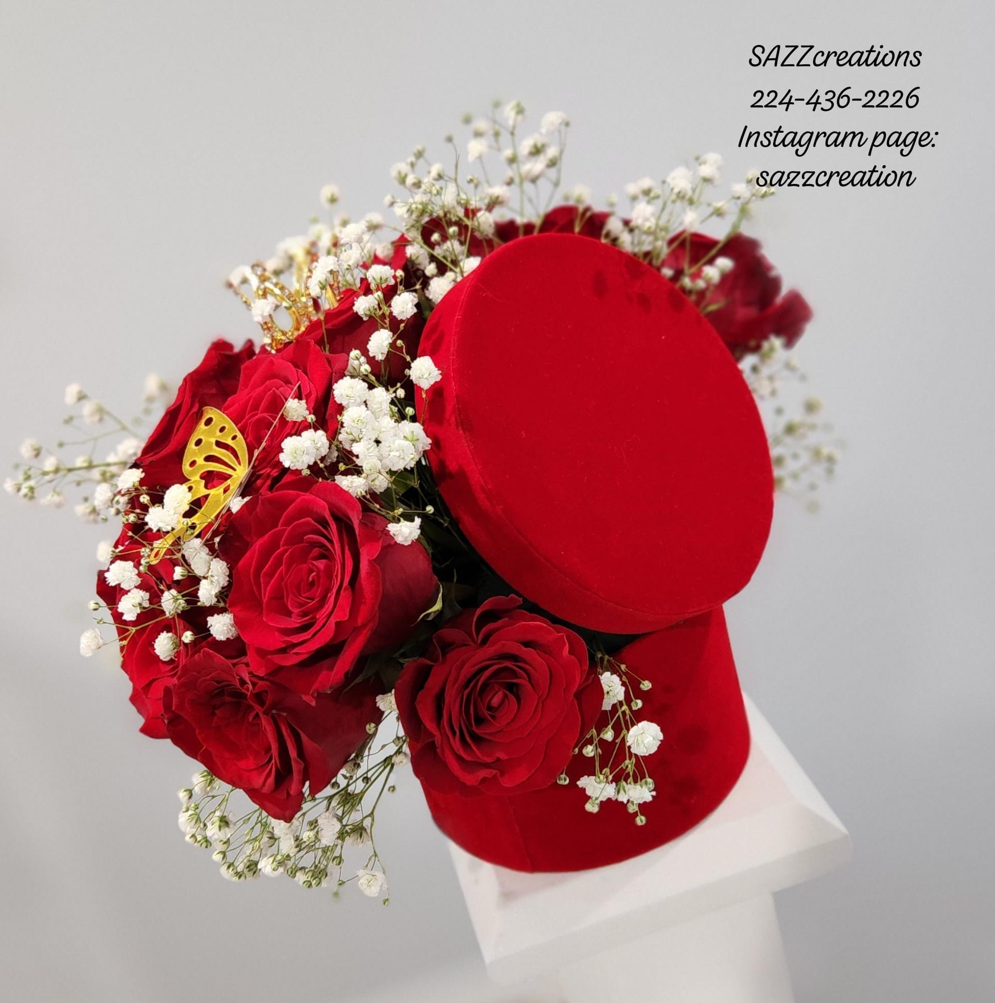 Red roses with baby's breath and gold crown arranged around a red velvet ring gift box